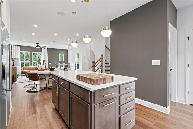 kitchen with ceiling fan, light wood-type flooring, open floor plan, and light countertops
