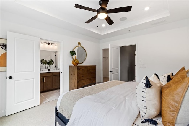bedroom featuring ensuite bath, a raised ceiling, recessed lighting, and a ceiling fan