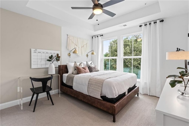 bedroom featuring light carpet, visible vents, a raised ceiling, and baseboards