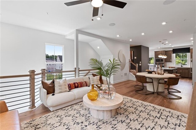 living area featuring ceiling fan with notable chandelier, light wood-style flooring, recessed lighting, and baseboards