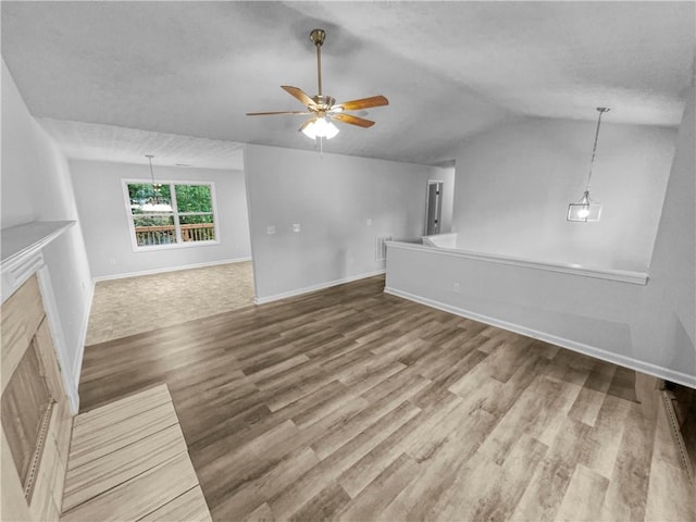 unfurnished living room with ceiling fan, a textured ceiling, baseboards, wood finished floors, and lofted ceiling