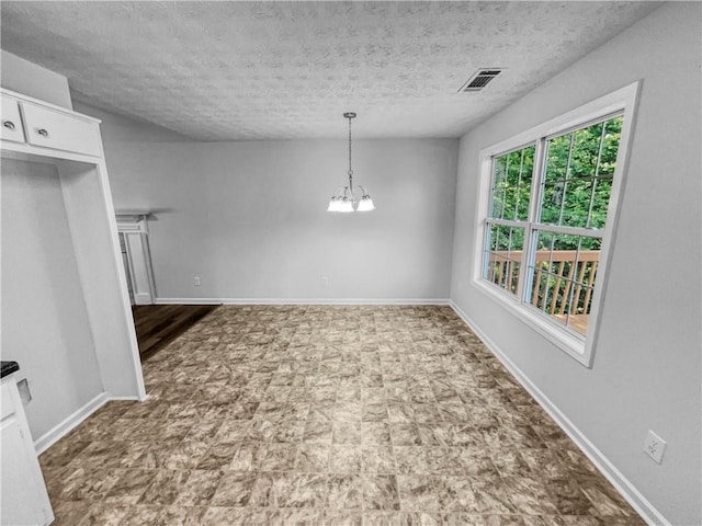unfurnished dining area with a textured ceiling, visible vents, baseboards, tile patterned floors, and a chandelier