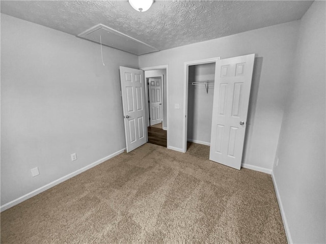 unfurnished bedroom featuring a closet, baseboards, carpet, and attic access