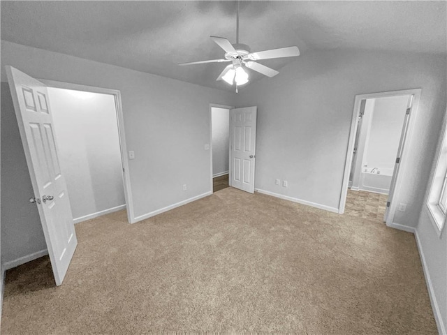unfurnished bedroom featuring baseboards, carpet, vaulted ceiling, and connected bathroom