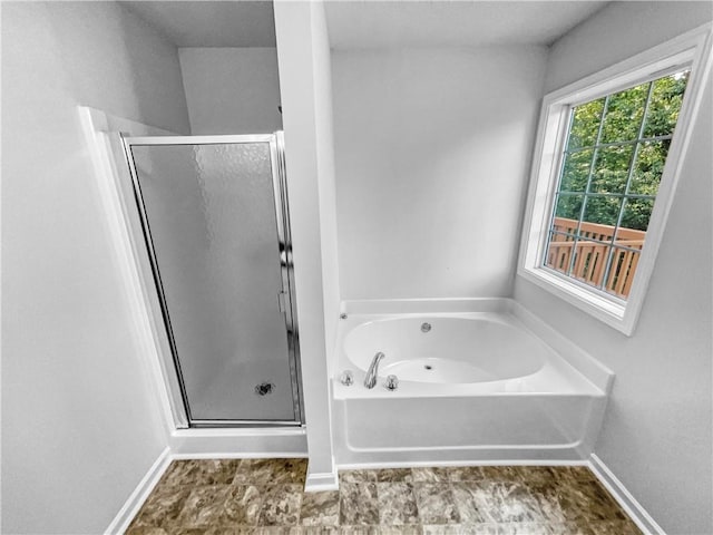 full bath with baseboards, a bath, and a shower stall