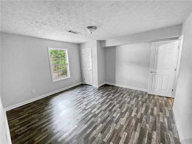 unfurnished bedroom with visible vents, a closet, dark wood-style flooring, baseboards, and a textured ceiling