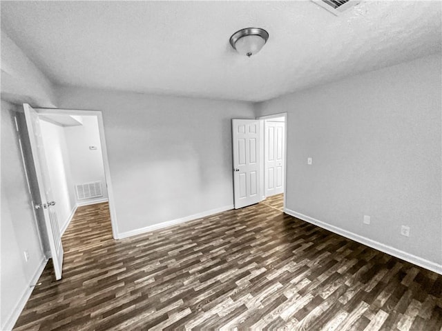 unfurnished bedroom featuring baseboards, dark wood finished floors, a textured ceiling, and visible vents