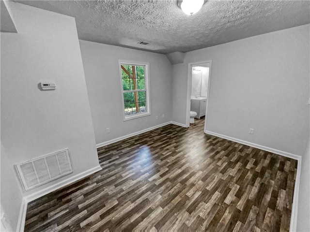 empty room with baseboards, dark wood-style floors, a textured ceiling, and visible vents