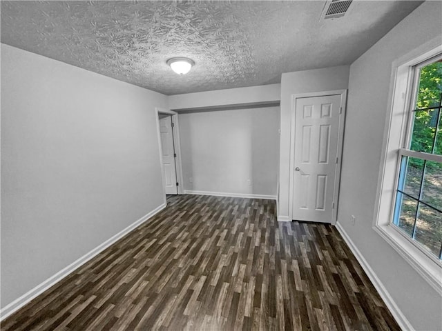 unfurnished bedroom with baseboards, a textured ceiling, and wood finished floors