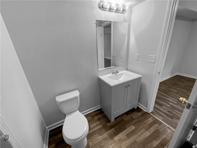 bathroom with toilet, baseboards, wood finished floors, and vanity