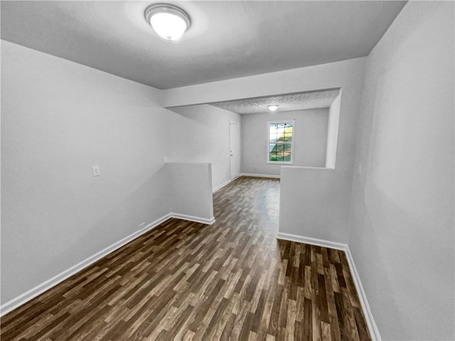 empty room with baseboards and dark wood-style floors
