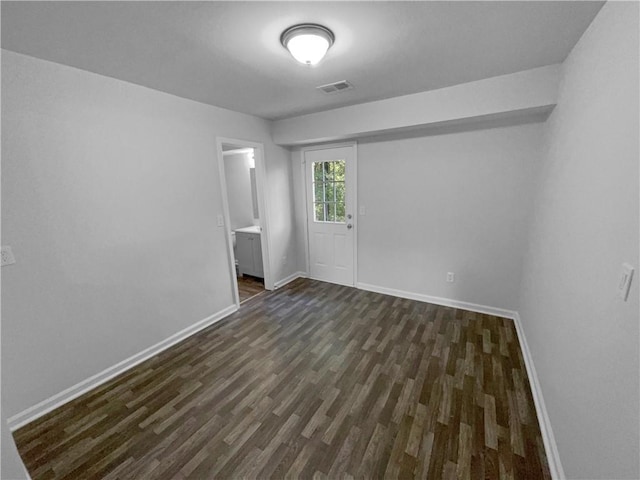 empty room featuring baseboards, visible vents, and dark wood-type flooring