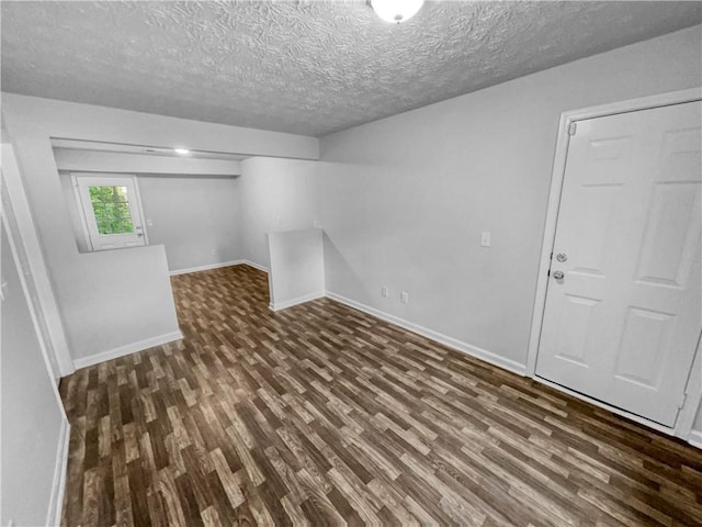 basement featuring baseboards, a textured ceiling, and wood finished floors