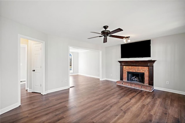 unfurnished living room featuring a brick fireplace, dark wood-style floors, and baseboards