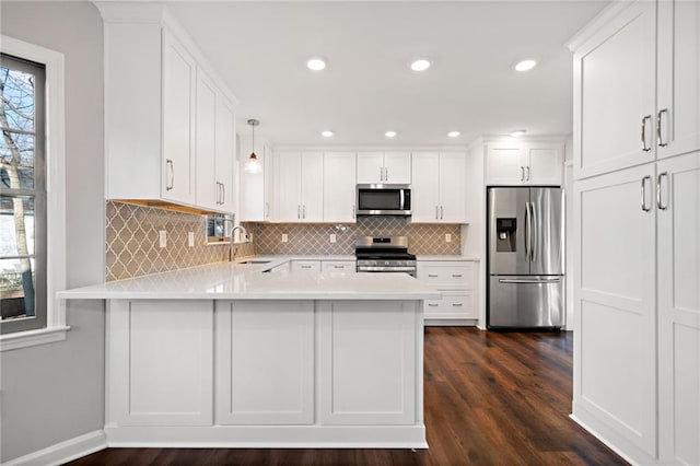 kitchen featuring a sink, white cabinetry, appliances with stainless steel finishes, a peninsula, and light countertops