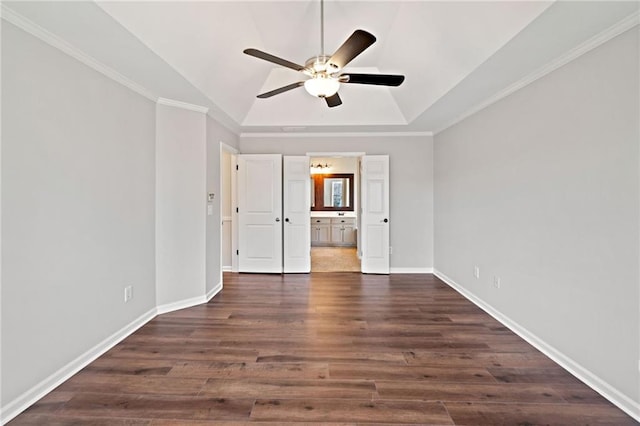 empty room with a ceiling fan, a raised ceiling, dark wood-style floors, and baseboards