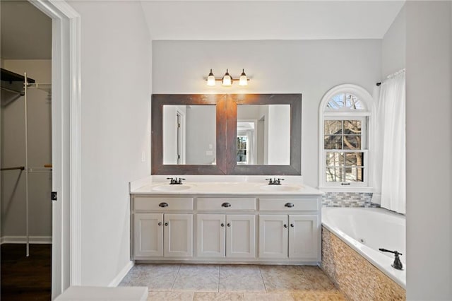 bathroom featuring a sink, a jetted tub, double vanity, and tile patterned floors