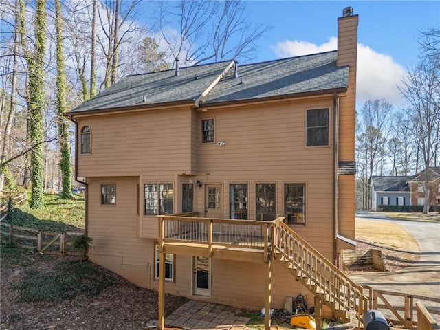 back of house with a wooden deck, a chimney, stairs, and fence