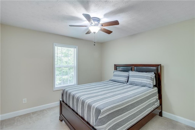 bedroom with light colored carpet, a ceiling fan, baseboards, and a textured ceiling
