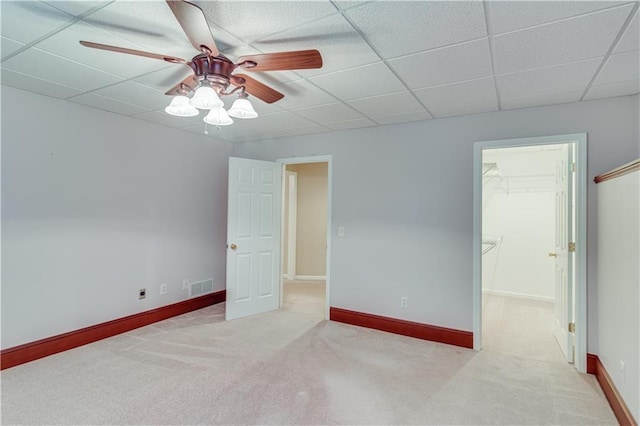 unfurnished bedroom with visible vents, baseboards, carpet floors, a spacious closet, and a drop ceiling