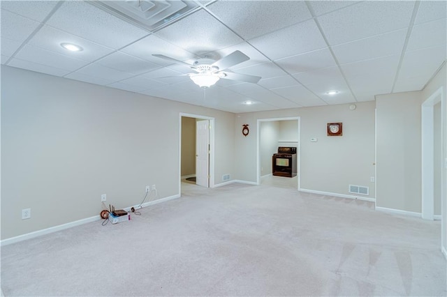 unfurnished room with ceiling fan, light colored carpet, baseboards, a drop ceiling, and visible vents