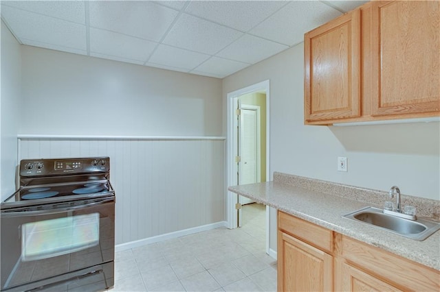 kitchen with black electric range oven, a sink, light countertops, light brown cabinets, and a drop ceiling