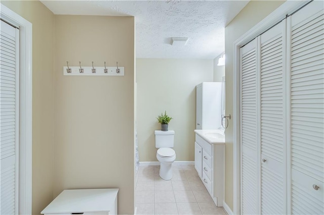 full bathroom with a closet, vanity, toilet, baseboards, and tile patterned floors