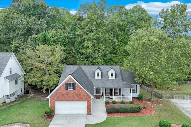 new england style home featuring brick siding, a garage, a front yard, concrete driveway, and covered porch