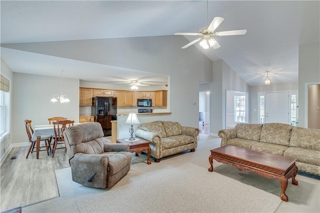 living room featuring baseboards, light wood-style flooring, ceiling fan with notable chandelier, and high vaulted ceiling