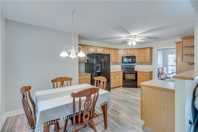 kitchen featuring light brown cabinetry, a sink, light countertops, light wood-style flooring, and black appliances