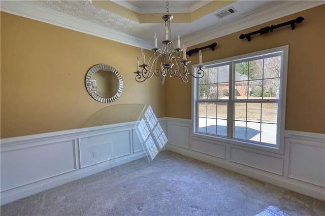 empty room featuring an inviting chandelier, visible vents, a tray ceiling, and carpet flooring