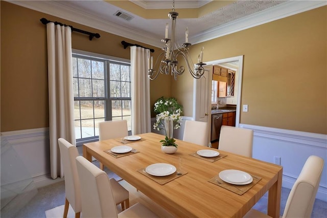 dining space with a chandelier, visible vents, wainscoting, a wealth of natural light, and crown molding