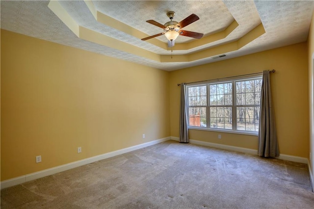 carpeted spare room featuring a tray ceiling, visible vents, ceiling fan, a textured ceiling, and baseboards