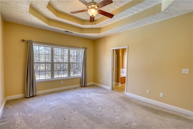 carpeted spare room featuring a raised ceiling, visible vents, a ceiling fan, a textured ceiling, and baseboards