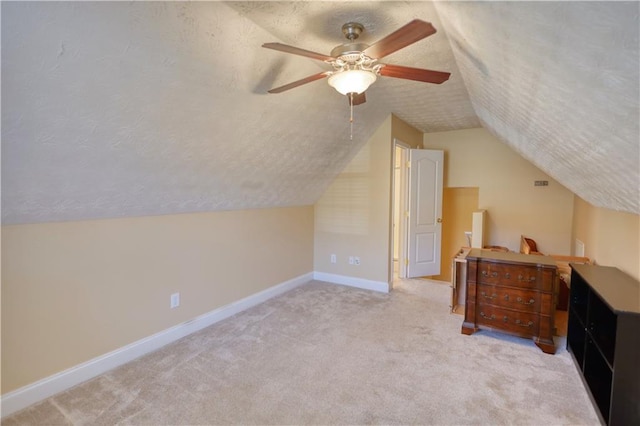 bonus room featuring a textured ceiling, a ceiling fan, baseboards, vaulted ceiling, and carpet