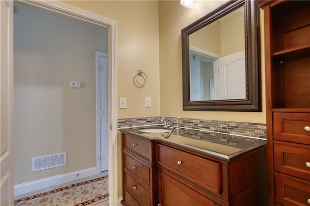 bathroom featuring baseboards, visible vents, vanity, and decorative backsplash