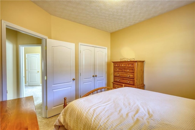 bedroom with a textured ceiling, a closet, and light colored carpet