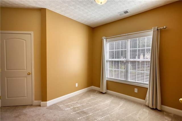 empty room with a textured ceiling, carpet, visible vents, and baseboards