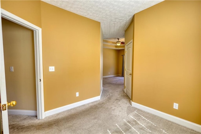 spare room featuring a textured ceiling, carpet flooring, and baseboards