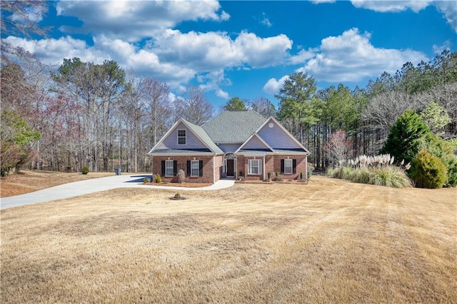 craftsman-style home with driveway, brick siding, and a front yard