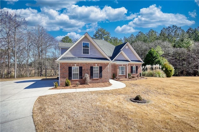 craftsman inspired home with driveway, brick siding, and a front yard