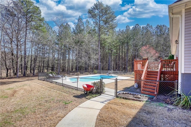 view of pool with fence, stairs, a lawn, a wooden deck, and a fenced in pool