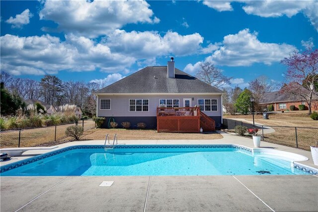 outdoor pool with a diving board, a wooden deck, and fence