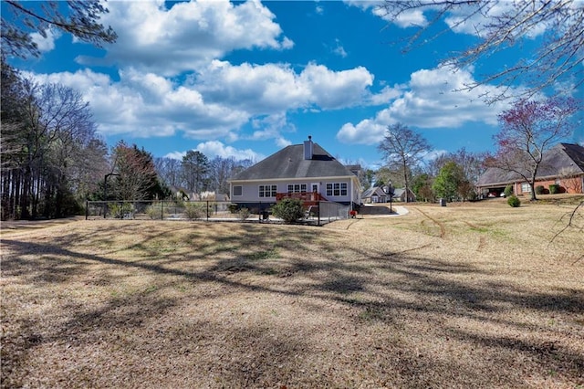 rear view of house with a lawn and fence