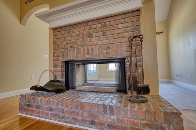 room details featuring visible vents, a fireplace, baseboards, and wood finished floors