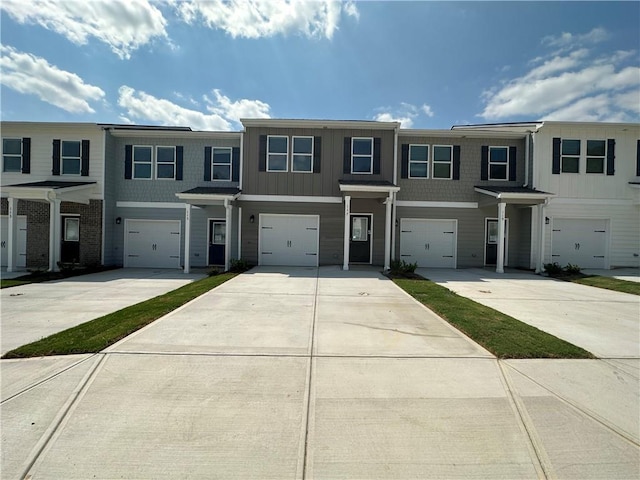 multi unit property featuring a garage, driveway, and board and batten siding