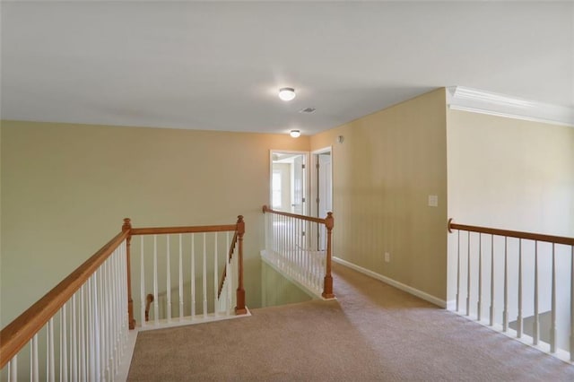 hallway featuring baseboards, an upstairs landing, and carpet flooring