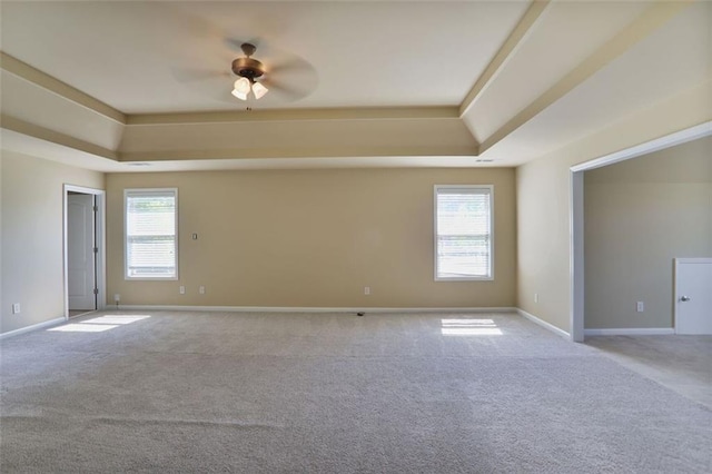 unfurnished room featuring a raised ceiling, ceiling fan, and carpet flooring