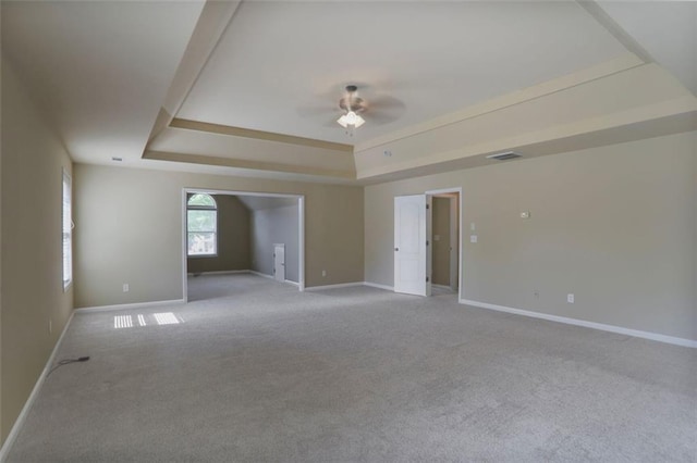 unfurnished room with visible vents, baseboards, a raised ceiling, a ceiling fan, and carpet floors