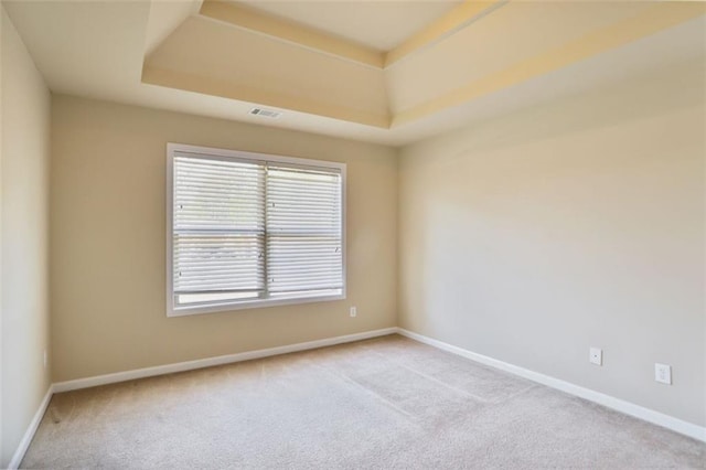spare room with visible vents, baseboards, a raised ceiling, and carpet flooring